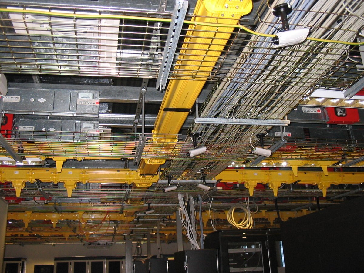 Ο πρώτος διάδρομος datacenter, 2004: κίτρινες σχάρες καλωδίων πάνω από μαύρες καμπίνες