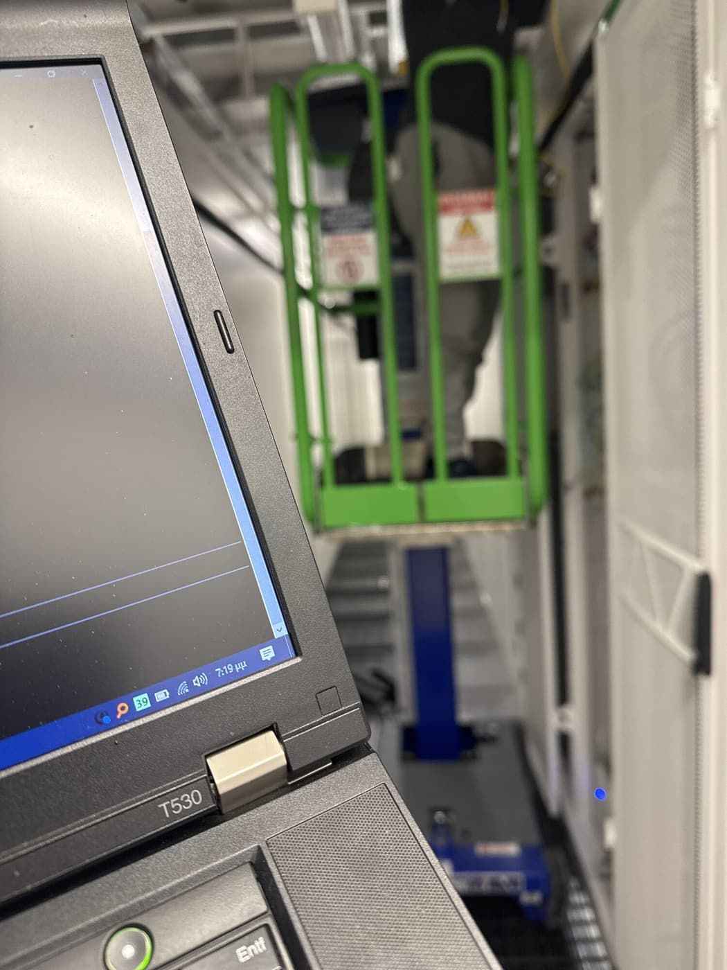An engineer cabling from the lift while the laptop tracks every connection